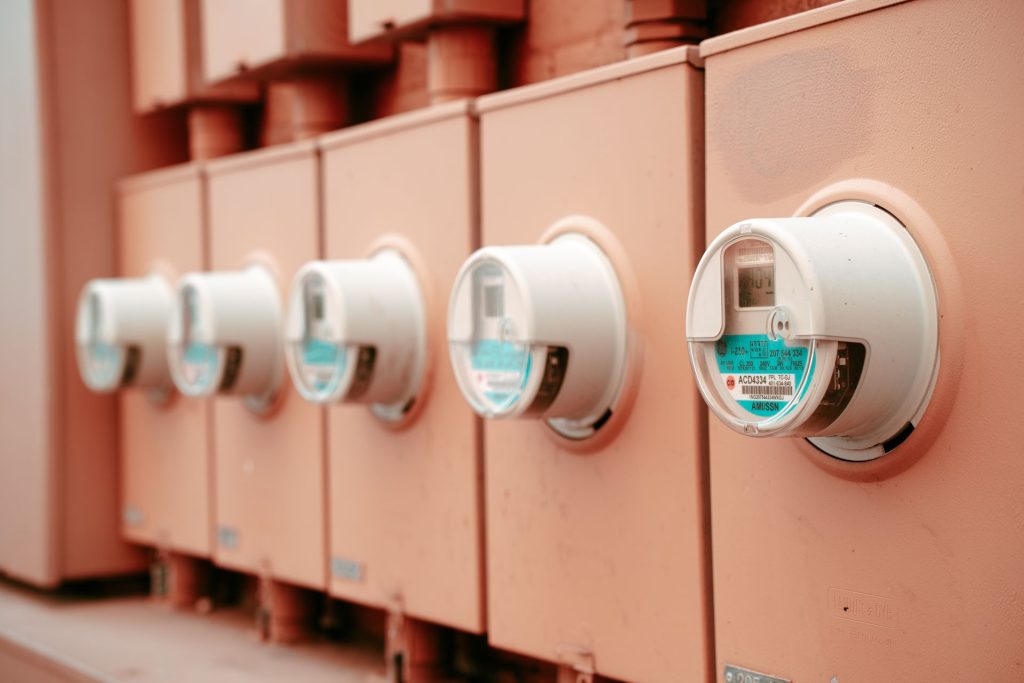 A row of modern smart electricity meters mounted on an exterior wall.